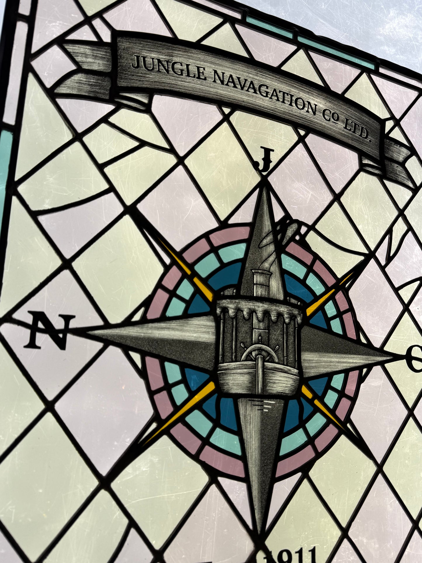Stained glass panel with a compass design and 'Jungle Navigation Co. Ltd.' text. Jungle Cruise Boat