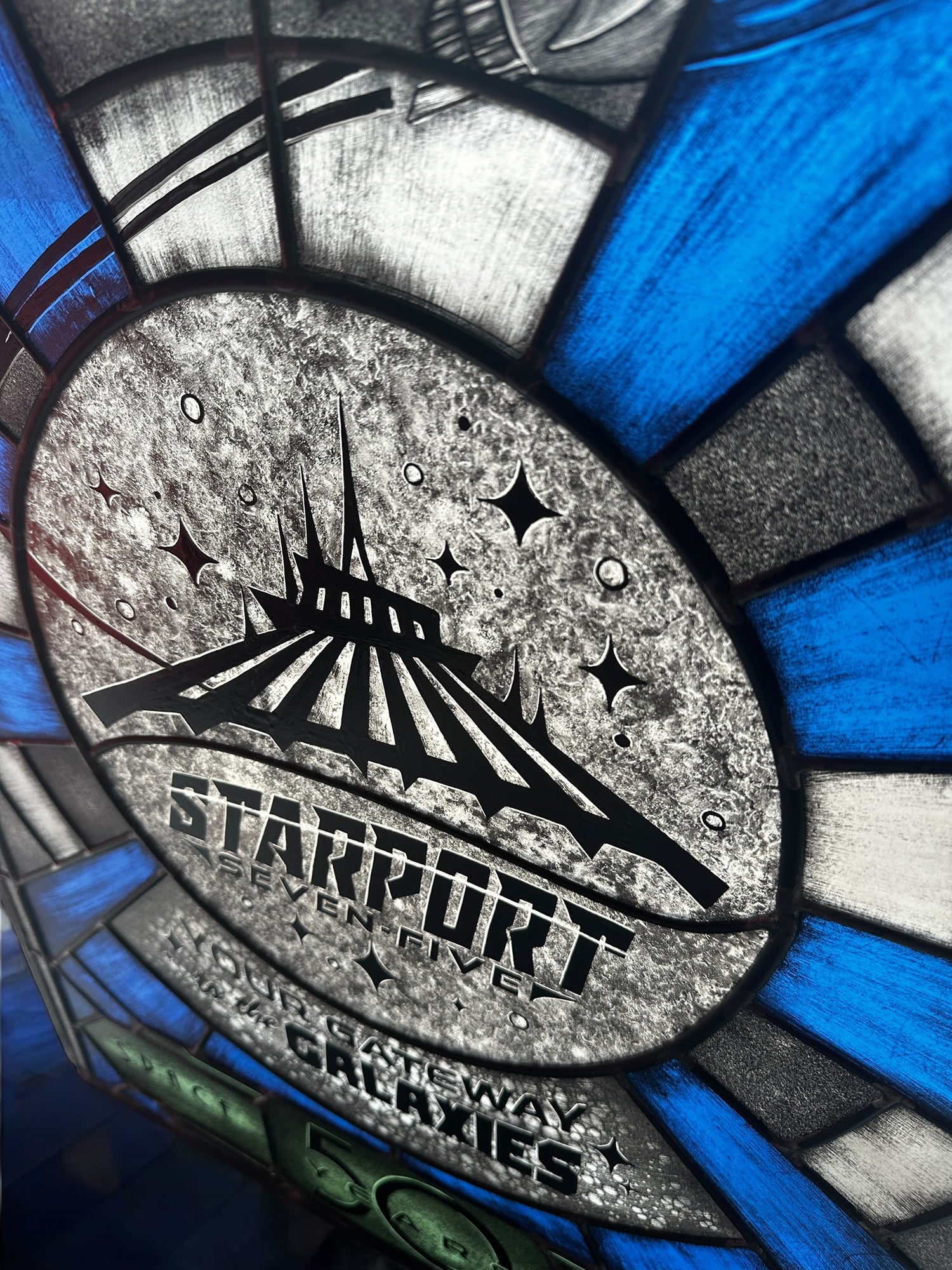 Stylized sign with 'Starport Seven Five' design,  stained glass. Blue and white launch tunnel background. '50 years Space Mountain' text. rocket with astronaut blasting off. 'Your Gateway to the Galaxies' text.