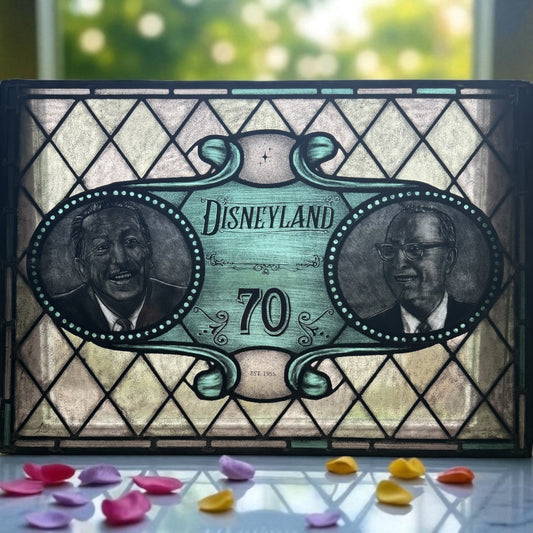 Decorative stained glass panel with 'Disneyland 70' and portraits on a  window surface. Walt and Roy Disney faces. Flower petals surround the window